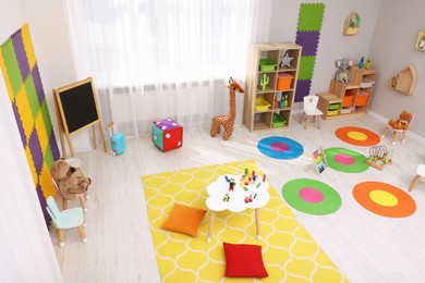 Child`s playroom with different toys and furniture, above view. Cozy kindergarten interior