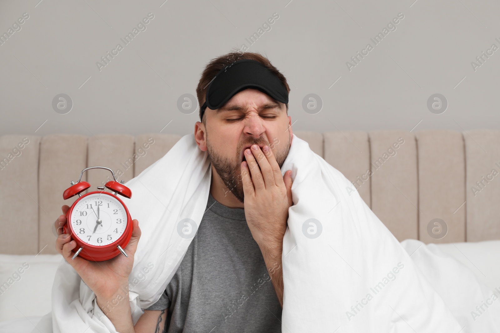 Photo of Overslept man with alarm clock in bed. Being late concept