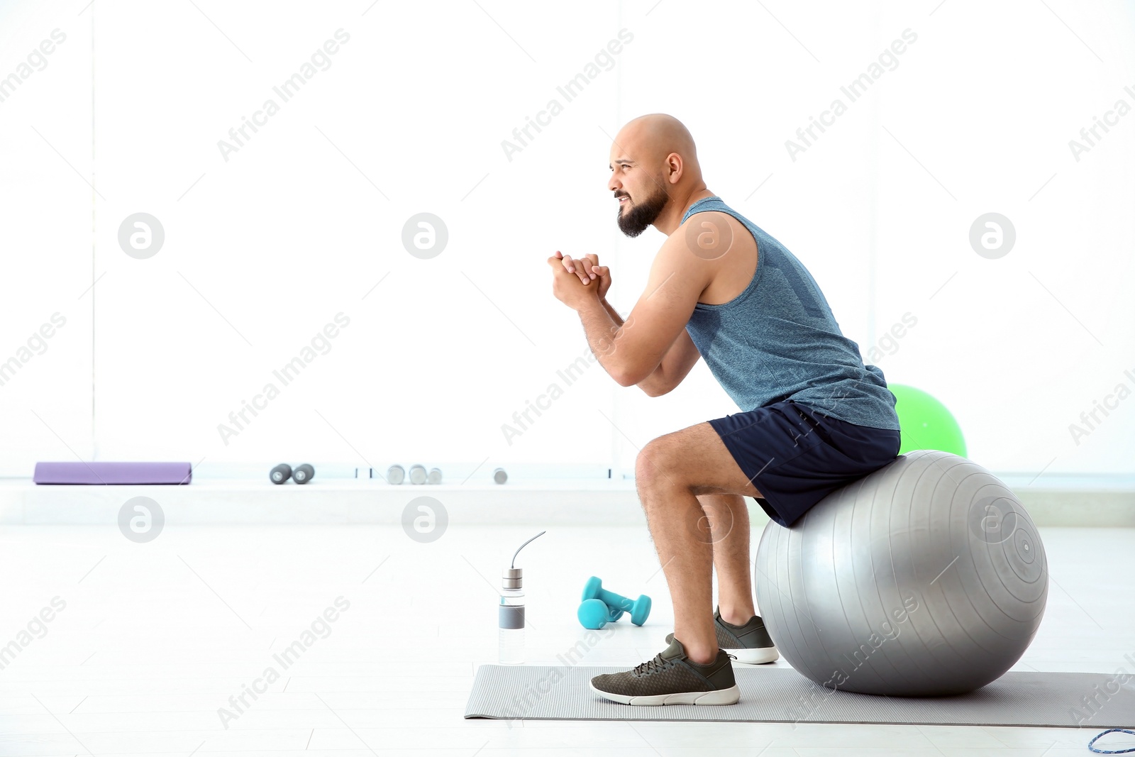 Photo of Overweight man doing exercise with fitness ball in gym