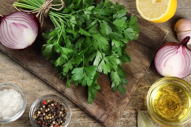 Board with fresh parsley, spices and other products on wooden table, flat lay