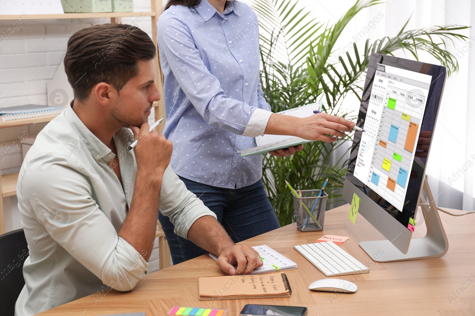 Photo of Colleagues working with calendar app on computer in office