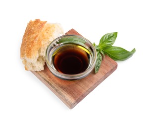 Photo of Bowl of organic balsamic vinegar with oil, basil and bread isolated on white
