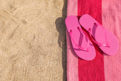Photo of Beach towel and slippers on sand, top view. Space for text