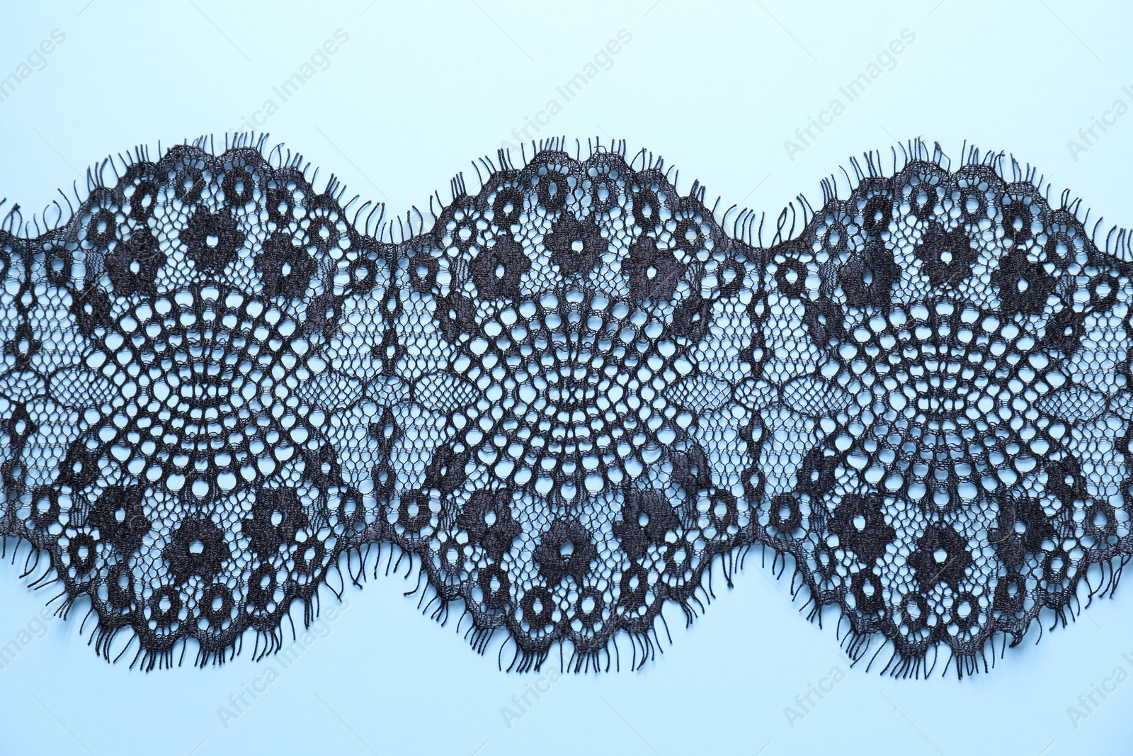 Photo of Black lace on light blue background, top view