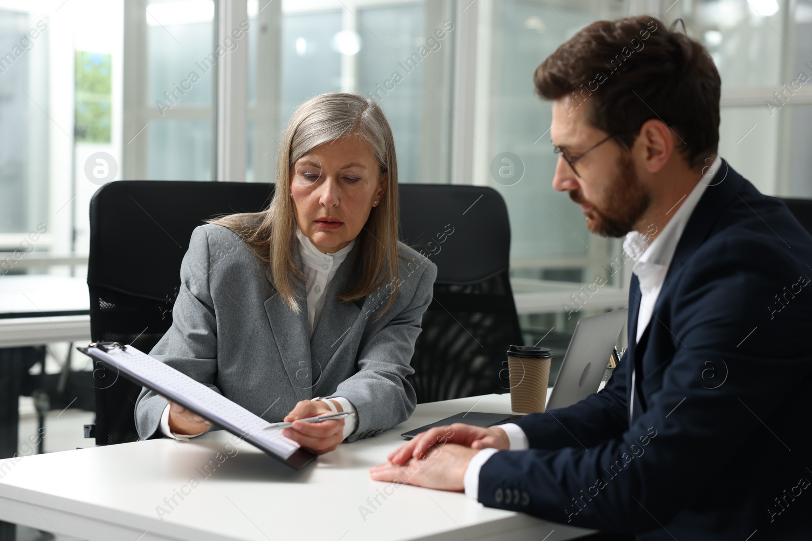 Photo of Lawyer with clipboard working with client at table in office
