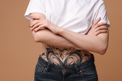 Photo of Woman with cool tattoos on belly against beige background, closeup