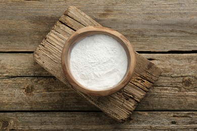 Baking powder in bowl on wooden table, top view