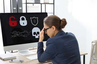 Photo of Office worker in front of computer with warning about virus attack on screen