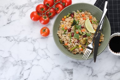 Photo of Tasty fried rice with vegetables served on white marble table, flat lay. Space for text