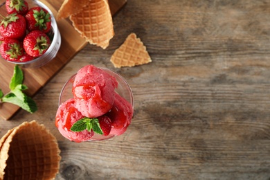 Photo of Flat lay composition with delicious strawberry ice cream on wooden table, space for text