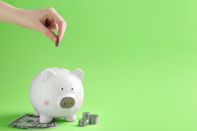 Photo of Financial savings. Woman putting coin into piggy bank on green background, closeup. Space for text