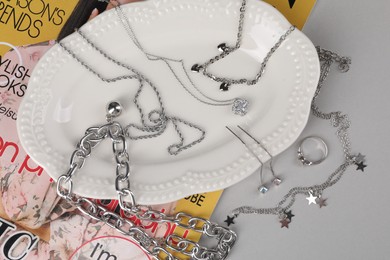 Metal chains and other different accessories on light table, flat lay. Luxury jewelry