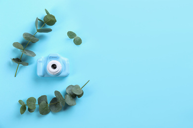 Photo of Toy camera and eucalyptus on light blue background, top view. Space for text