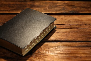 Photo of Bible on wooden table, space for text. Christian religious book