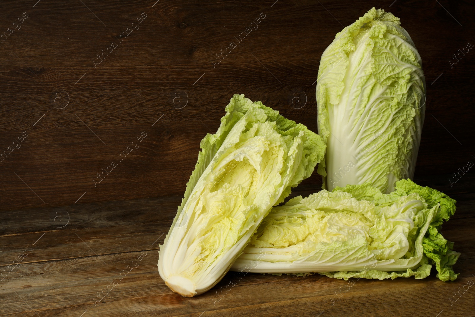 Photo of Fresh ripe Chinese cabbages on table against wooden background. Space for text