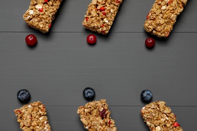 Tasty granola bars on grey wooden table, flat lay. Space for text