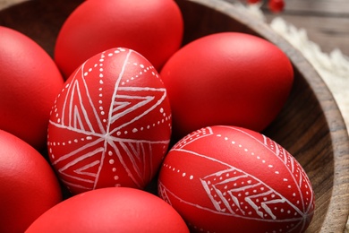 Photo of Red painted Easter eggs in wooden bowl, closeup