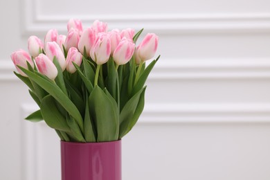 Photo of Beautiful bouquet of fresh pink tulips near white wall. Space for text