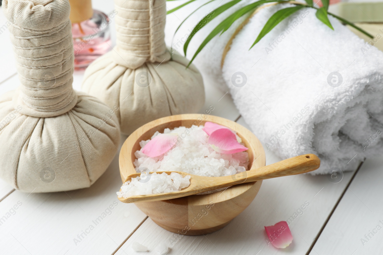 Photo of Spa composition. Towel, herbal bags and sea salt on white wooden table