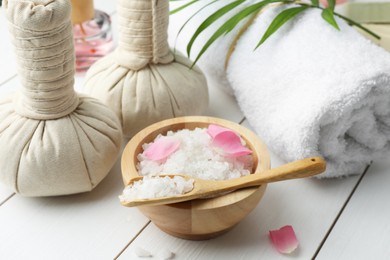 Spa composition. Towel, herbal bags and sea salt on white wooden table