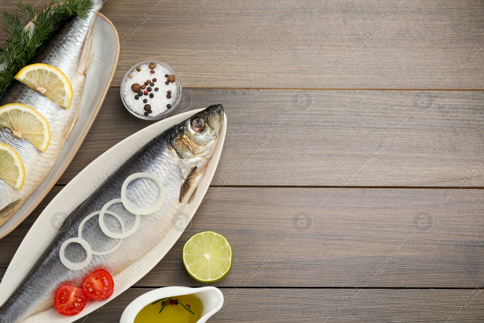 Photo of Delicious salted herrings and ingredients on wooden table, flat lay. Space for text