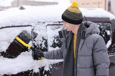 Photo of Man cleaning snow from car window outdoors