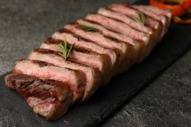 Photo of Delicious grilled beef steak with rosemary on dark gray table, closeup