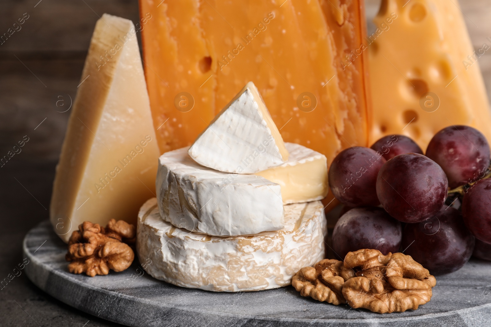 Photo of Composition with assorted cheese, grapes and walnuts on table against wooden background