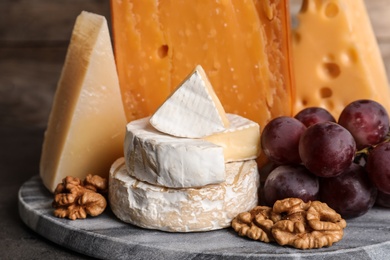Photo of Composition with assorted cheese, grapes and walnuts on table against wooden background