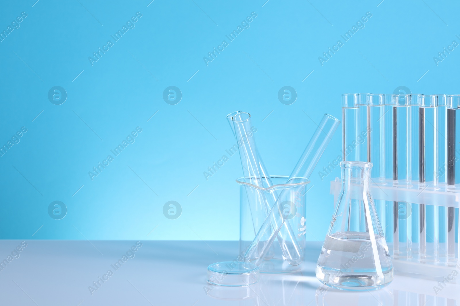 Photo of Laboratory analysis. Different glassware on table against light blue background, space for text