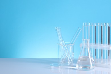 Photo of Laboratory analysis. Different glassware on table against light blue background, space for text