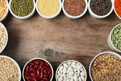 Frame made with different grains and cereals on wooden table, top view. Space for text