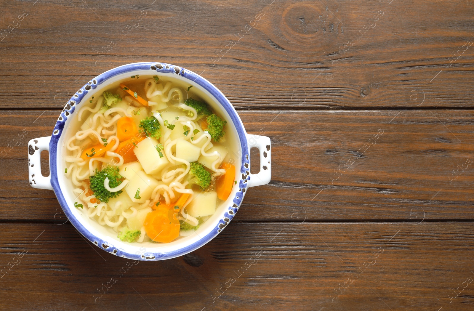 Photo of Dish of fresh homemade vegetable soup on wooden background, top view. Space for text