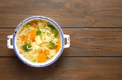 Dish of fresh homemade vegetable soup on wooden background, top view. Space for text