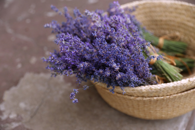 Photo of Wicker basket with lavender flowers on cement floor outdoors, closeup