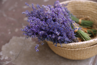 Wicker basket with lavender flowers on cement floor outdoors, closeup