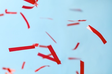 Photo of Shiny red confetti falling down on light blue background
