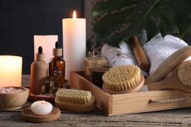 Composition with different spa products and burning candles on wooden table