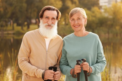 Photo of Senior man and woman with Nordic walking poles outdoors
