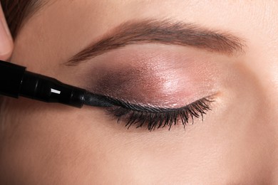 Photo of Artist applying black eyeliner onto woman's face, closeup