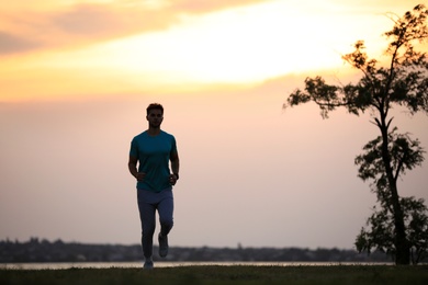 Photo of Young man running outdoors in evening. Space for text