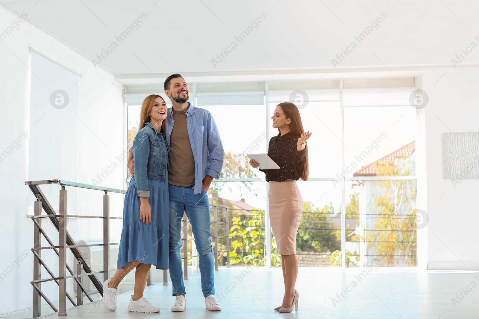 Photo of Female real estate agent showing new house to couple, indoors