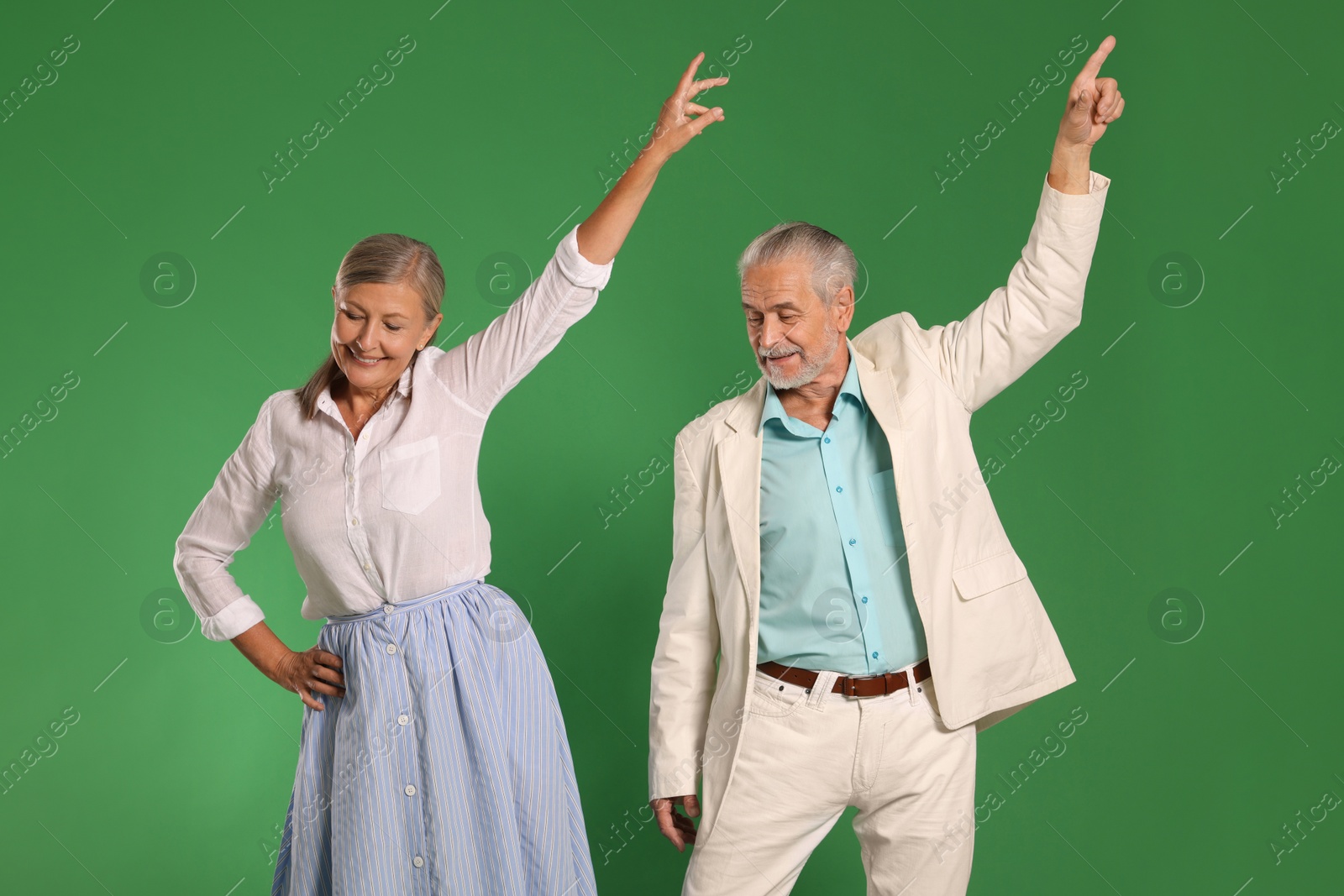 Photo of Senior couple dancing together on green background