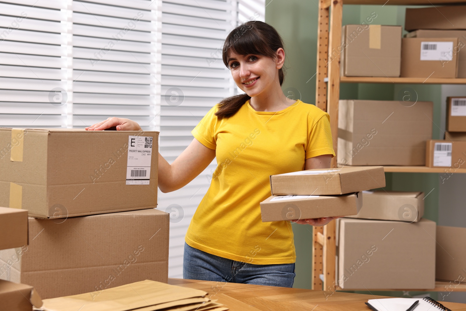 Photo of Parcel packing. Post office worker with parcels at wooden table indoors