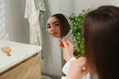 Photo of Beautiful woman looking in mirror in bathroom