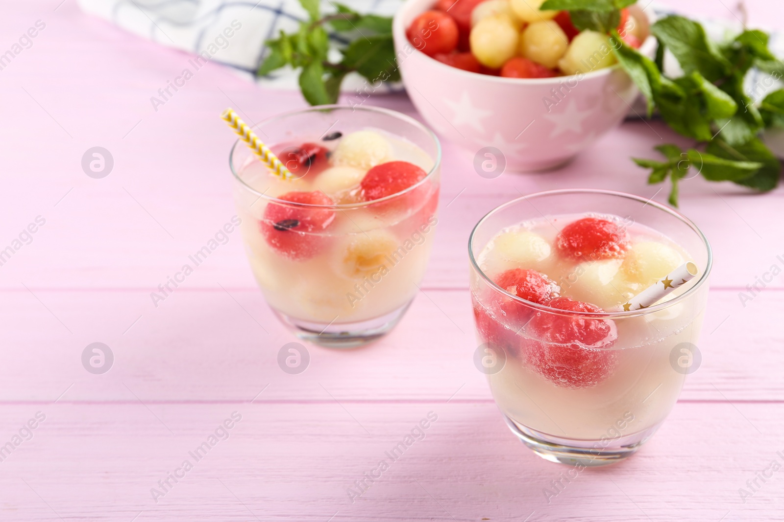 Photo of Glasses of melon and watermelon ball cocktail on pink wooden table. Space for text