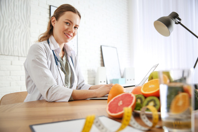 Nutritionist working with laptop at desk in office