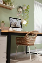 Photo of Stylish workplace with computer, lamp and houseplant near olive wall at home