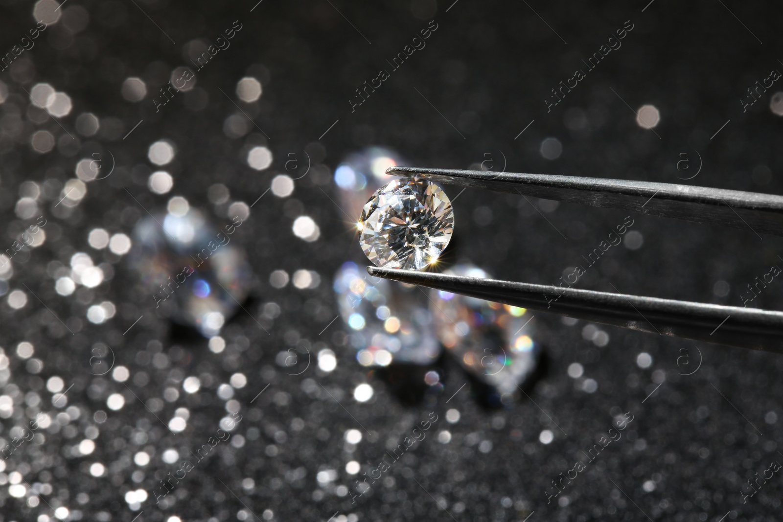 Photo of Tweezers with beautiful diamond on dark shiny background, closeup. Space for text