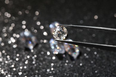 Photo of Tweezers with beautiful diamond on dark shiny background, closeup. Space for text